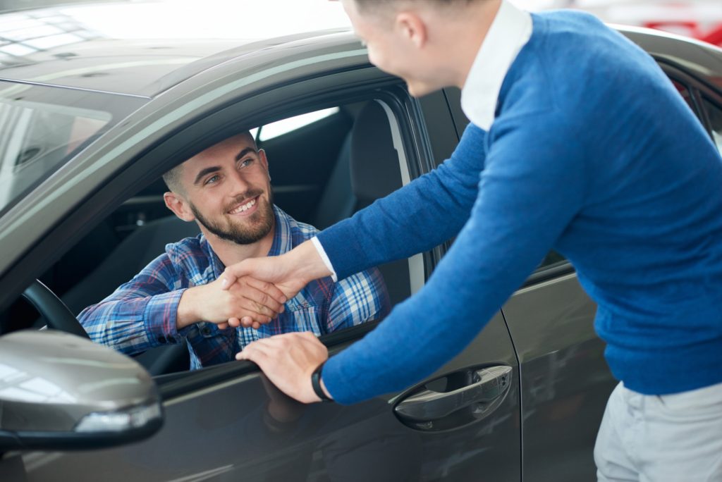 Car seller and customer handshake in car dealership